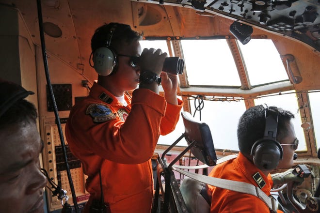 A crew of an Indonesian Air Force C-130 airplane of the 31st Air Squadron uses a binocular to scan the horizon during a search operation for the missing AirAsia flight 8501 jetliner over the waters of Karimata Strait in Indonesia, Monday, Dec. 29, 2014. Search planes and ships from several countries on Monday were scouring Indonesian waters over which an AirAsia jet disappeared, more than a day into the region’s latest aviation mystery. AirAsia Flight 8501 vanished Sunday in airspace thick with storm clouds on its way from Surabaya, Indonesia, to Singapore.
