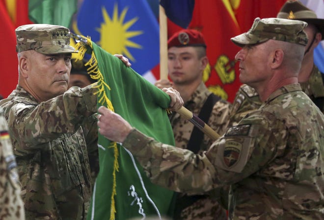 Commander of the International Security Assistance Force (ISAF), Gen. John Campbell, left, and Command Sgt. Maj. Delbert Byers open the "Resolute Support" flag during a ceremony at the ISAF headquarters in Kabul, Afghanistan, Sunday, Dec. 28, 2014. The United States and NATO formally ended their war in Afghanistan on Sunday with the ceremony at their military headquarters in Kabul as the insurgency they fought for 13 years remains as ferocious and deadly as at any time since the 2001 invasion that unseated the Taliban regime following the Sept. 11 attacks. (AP Photo/Massoud Hossaini)