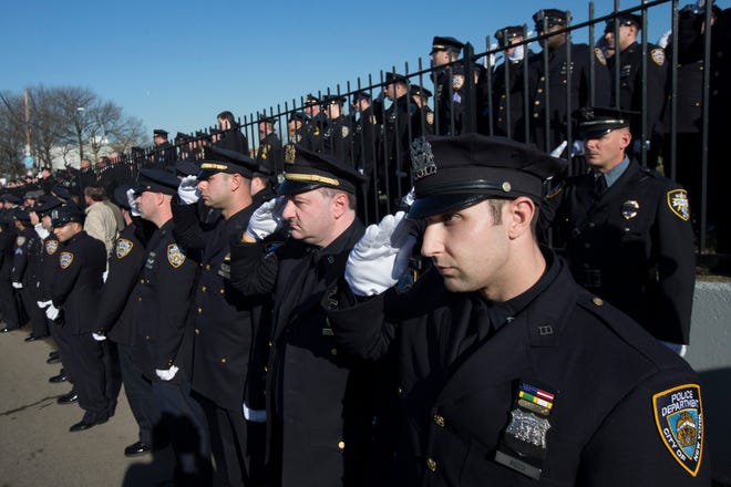 Police officers salute as the hearse of New York city police officer Rafael Ramos drives along his funeral procession route in the Glendale section of Queens, Saturday, Dec. 27, 2014, in New York.