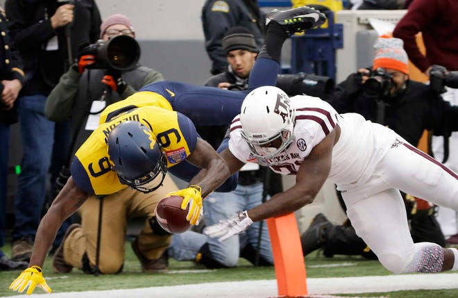 West Virginia safety KJ Dillon (9) dives into the end zone ahead of Texas A&M running back Tra Carson, right, as Dillon runs a pass interception back 35 yards for a touchdown in the first half of the Liberty Bowl NCAA college football game, Monday, Dec. 29, 2014, in Memphis, Tenn. (AP Photo/Mark Humphrey)