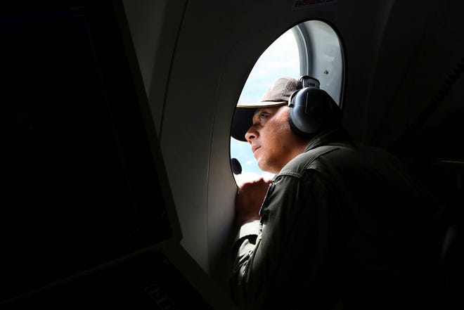 A crew member of Indonesian Navy CN-235 airplane looks out of the window during a search operation for the missing AirAsia flight 8501 over the waters off Bangka Island, Indonesia, Tuesday, Dec. 30, 2014. Six bloated bodies and debris seen floating in Indonesian waters Tuesday painful ended the mystery of AirAsia Flight 8501, which crashed into the Java Sea and was lost to searchers for more than two days. (AP Photo/Tatan Syuflana)