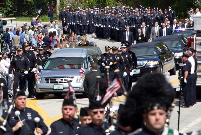 In this Wednesday May 21, 2014 file photo, the hearse carrying the body of Brentwood police Officer Stephen Arkell makes its way to a memorial service in Exeter, N.H. Arkell was shot and killed when he responded to a domestic dispute call. Arkell's death was one of New Hampshire's top stories for 2014. (AP Photo/Jim Cole, File)