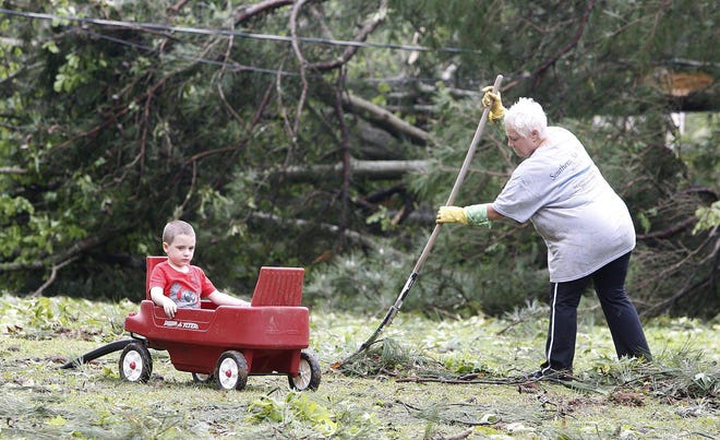 Gayle Turner rakes up debris while Cole Collins sits in his wagon at the home of Butch and Janis Hanks onTuesday April 29, 2014. Collins is the grandson of the Butch and Janis Hanks whose home was damaged when storms blew through south Tuscaloosa late Monday night toppling hundreds of trees and damaging several homes. staff photo | Robert Sutton
