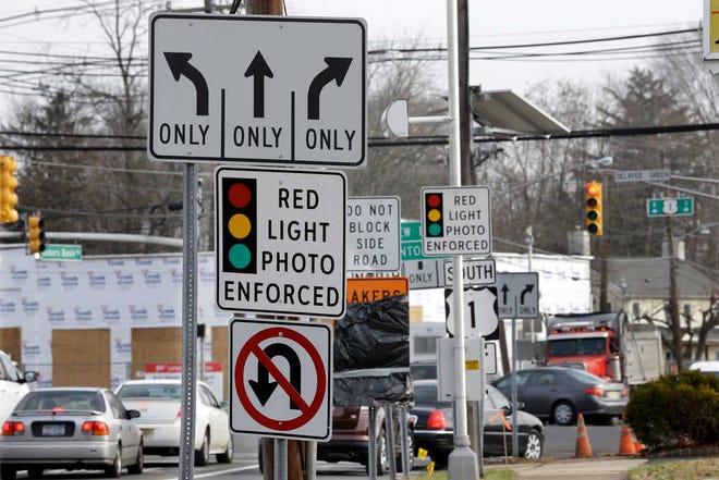 FILE - In a Tuesday, Dec. 16, 2014 file photo, traffic passes a red light photo enforcement sign below a red light camera at the intersection of Route 1 and Franklin Corner Road, in Lawrence Township, N.J. New Jersey legislators recently discontinued the state's red light camera pilot program after five years. The number of red-light cameras nationwide is falling because of opposition from lawmakers and average Joes _ but the use of cameras to catch speeders is slowly rising, potentially signaling a new battleground.  (AP Photo/Mel Evans, File)