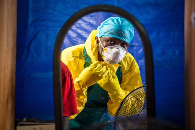 FILE - In this Thursday, Oct. 16, 2014 file photo, a healthcare worker dons in protective gear before entering an Ebola treatment center in the west of Freetown, Sierra Leone. Professors from three leading British universities say policies favoring international debt repayment over social spending contributed to the Ebola crisis by hampering health care in the three worst-hit West African countries. Conditions for loans from the International Monetary Fund prevented an effective response to the outbreak that has killed nearly 8,000 people, the academics allege in a report in The Lancet Global Health journal this month. (AP Photo/Michael Duff, File)
