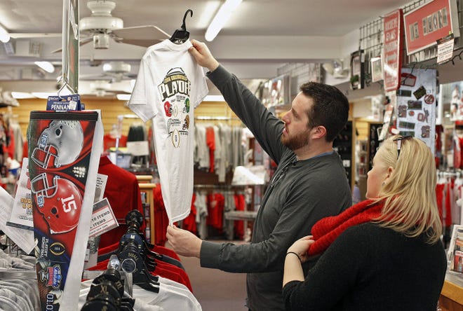 At Conrads College Gifts on W. Lane Avenue, across from the Ohio State University campus, Matt Plank, left, and his girlfriend Ashley Topp look over the selection of Sugar Bowl and college playoff T-shirts. They each made a purchase on Tuesday.