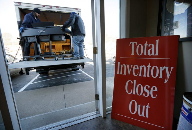 In this Dec. 3, 2014, photo, workers load a keyboard onto a truck at the Foster Family Music Center piano store, in Bettendorf, Iowa. Foster is closing his store this month after being in business for nearly 30 years.