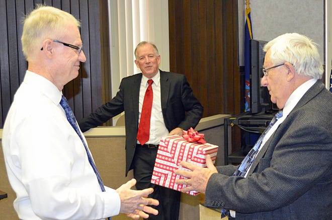 Magistrate Judge David Coyle (left) presents retiring attorney and public defender Eric Goodwin with a gift while attorney Joe Hayes watches. Goodwin retired after 43 years practicing law in Branch County. He was honored Tuesday with a reception in District Court. DON REID PHOTO