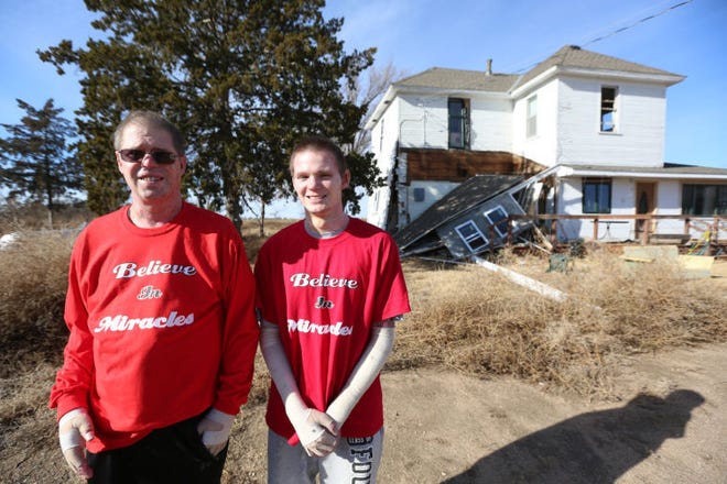 Scott and Alex Kreger stand in front of the house that exploded when they were replacing a water heater in October.
