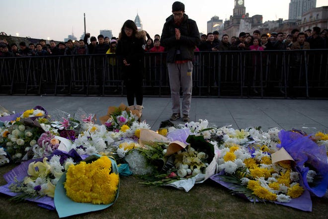 A man and a woman pray after laying flowers at the site of a deadly stampede in Shanghai, China, Thursday, Jan. 1, 2015. People unable to contact friends and relatives streamed into hospitals Thursday, anxious for information after a stampede during New Year's celebrations in Shanghai's historic waterfront area killed dozens of people in the worst disaster to hit one of China's showcase cities in recent years. (AP Photo/Ng Han Guan)