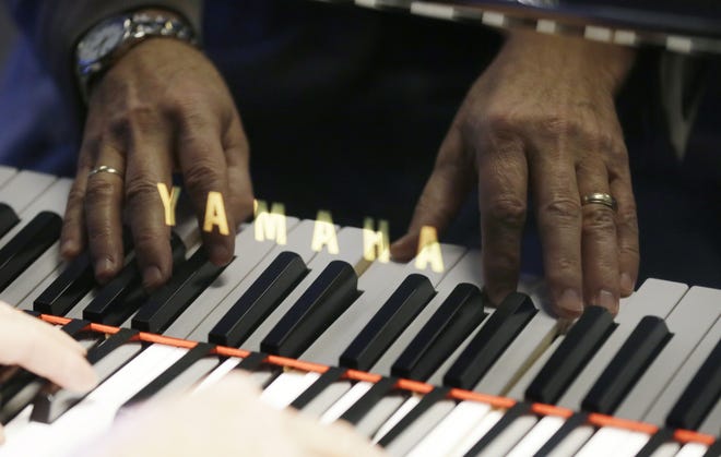In this Dec. 3, 2014, photo, Jim Foster’s hands are reflected as he plays a grand piano in his Foster Family Music Center piano store, in Bettendorf, Iowa. The number of stores dedicated to selling pianos is dwindling across the country as fewer people take up the instrument and those who do opt for a used piano or a less expensive electronic keyboard.