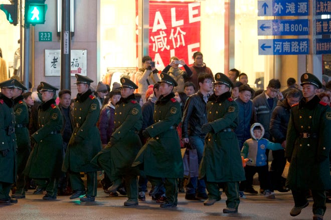 Chinese paramilitary policemen form human chains to guide pedestrians crossing a major intersection near the site of a deadly stampede in Shanghai, China, Thursday, Jan. 1, 2015. Thirty six died in a stampede during New Year's celebrations in downtown Shanghai, city officials said - the worst disaster to hit one of China's showcase cities in recent years.