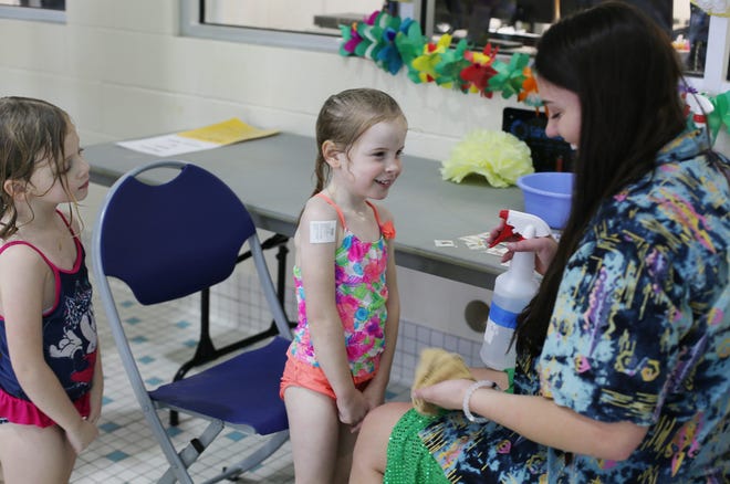 Morgan Babinski, 5, of Grand Rapids watches as her friend Kelsey Howard, 5, of Grand Haven gets a temporary tattoo from Lizzie Maher, 19, of Holland on Sat., Jan 3, at the Holland Community Aquatic Center's New Year Celebration. Emily Brouwer/Sentinel Staff