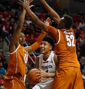 Texas Tech's Isaiah Manderson tries to shoot under pressure against Texas' Jonathan Holmes (10) and Myles Turner during their game on Saturday in Lubbock.