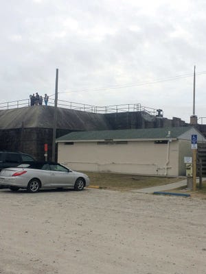 Kelly Quimby / Savannah Morning News - Visitors to Tybee Island's historic Fort Screven take in the sights - the beach, lighthouse and North Beach's sole public restroom facility - from atop Battery Garland Friday. City officials are planning to replace the old restroom facility beginning this year.
