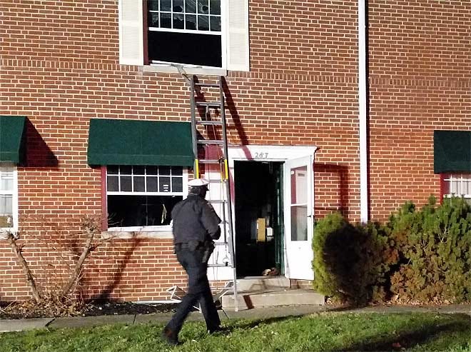 A Columbus police officer walks past an apartment on Mayfair Boulevard where a man was pulled out in life-threatening condition by firefighters.