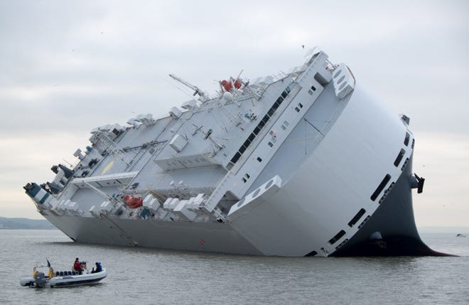 A small boat sails past the Hoegh Osaka car-transport ship that was run aground off southern England after it began to list. Twenty-five crew members were rescued by a helicopter and lifeboats after the ship developed problems on Saturday evening after leaving Southampton. A salvage operation is expected to take several days, although no oil is thought to have leaked from the ship.