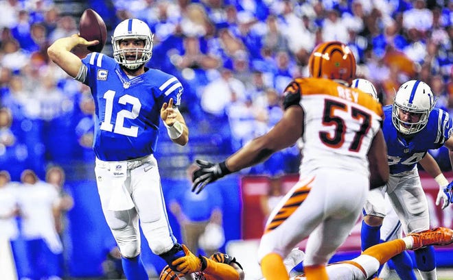 Indianapolis Colts quarterback Andrew Luck (12) throws a 36-yard touchdown pass as he is tackled by Cincinnati Bengals' Carlos Dunlap (96) during the second half of an NFL wildcard playoff football game Sunday, Jan. 4, 2015, in Indianapolis. (AP Photo/AJ Mast)