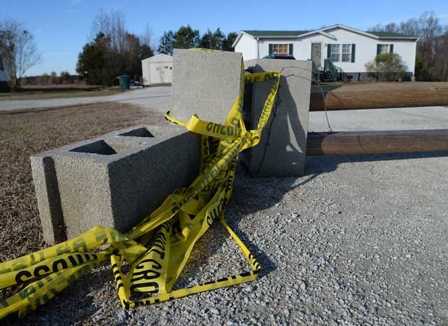 Crime scene tape wraps around cinder blocks as part of a makeshift gate Monday at the former residence of Melody and Paul Brown on Cobblestone Drive. The Lenoir County Sheriff’s Office believes the Browns were killed during a botched robbery Dec. 23.