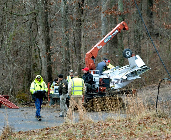 Salvage workers bring out part of a Piper PA-34's fuselage, wing, and landing gear from a crash site Sunday, Jan. 4, 2015 in Kuttawa, Ky. Officials from the National Transportation Safety Board arrived at the crash site Sunday in Kentucky in which a 7-year-old girl survived and four of her family members were killed. Authorities said the child, dressed in a short-sleeve shirt, shorts and one sock, walked about a mile (more than a kilometer) in near-freezing temperatures through thick briar patches and woods before finding a home where she sought help. The plane went down in a deeply wooded area and required special machinery to remove. (AP Photo/Timothy D. Easley)