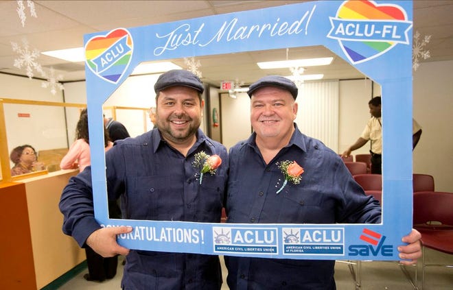 Edgard Perez, left, 40, and his spouse Charles Windham, right, 53, pose for a photo after they were married at the marriage license bureau, Tuesday, Jan. 6, 2015 in Miami. Miami-Dade Circuit Judge Sarah Zabel presided over Florida's first legally recognized same-sex marriages Monday afternoon. Still, most counties held off on official ceremonies until early Tuesday, when U.S. District Judge Robert L. Hinkle's ruling that Florida's same-sex marriage ban is unconstitutional took effect in all 67 counties. (AP Photo/Wilfredo Lee)