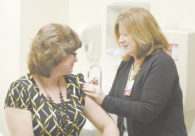 Registered nurse Kathy Reed, an infection preventionist at Affinity Medical Center, vaccinates Pam Hughes for the flu at the hospital. Health officials say it is not too late for people to get the flu shot.