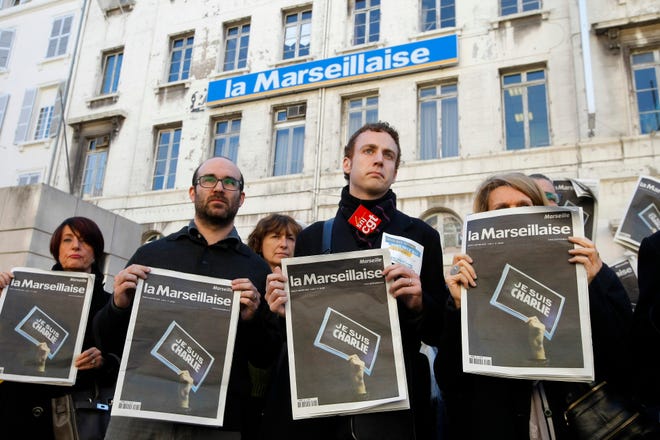 Employees and journalists of the newspaper "La Marseillaise" hold a journal of the day, reading "I am Charlie," in front of the newspaper building during a minute of silence in Marseille, southern France, Thursday, a day after masked gunmen stormed the offices of a satirical newspaper and killed 12 people.