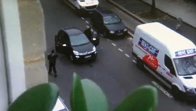 In this image made from amateur video recorded on Wednesday, Jan. 7, 2015 by Jordi Mir, masked gunman get into a car moments after shooting a police officer outside the offices of French satirical newspaper Charlie Hebdo in Paris. Paris residents captured chilling video images of two masked gunmen shooting a police officer after an attack at a French satirical newspaper. In the video, the gunmen armed with assault rifles are seen running up to an injured police officer, who lies squirming on the ground. The police officer raises his hands up before one of the assailants shoots him in the head at a close range. (AP Photo/Jordi Mir) NO SALES