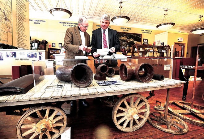 Uhrichsville Mayor Terry Culbertson (left) and Blair Hillyer look at old photographs behind a clay truck, used to haul pipe, at the Uhrichsville Clay Museum as a campaign to raise capital for the new museum kicks off Thursday in Uhrichsville.