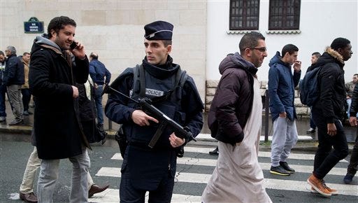 A French police officer stands guard outside the Grand Mosque as people arrive for Friday prayers, Paris, Friday, Jan. 9, 2015. French security forces struggled with two rapidly developing hostage-taking situations Friday, one northeast of Paris where two terror suspects were holed up with a hostage in a printing plant and the other an attack on a kosher market in Paris. (AP Photo/Michel Euler)