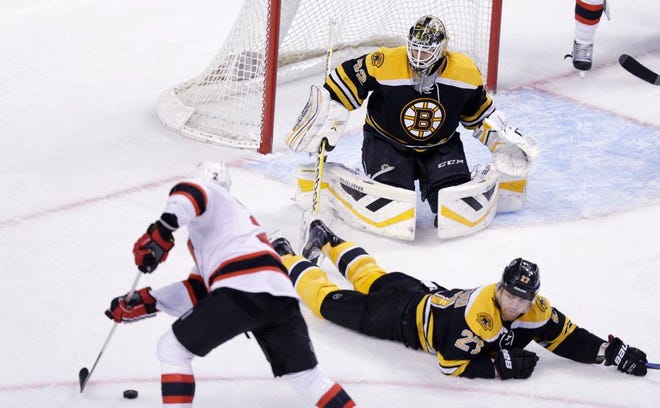 Boston Bruins defenseman Dougie Hamilton drops to the ice to prevent a shot on goalie Niklas Svedberg by New Jersey Devils defenseman Marek Zidlicky during the third period of an NHL hockey game in Boston, Thursday, Jan. 8, 2015. The Bruins shut out the Devils, 3-0.