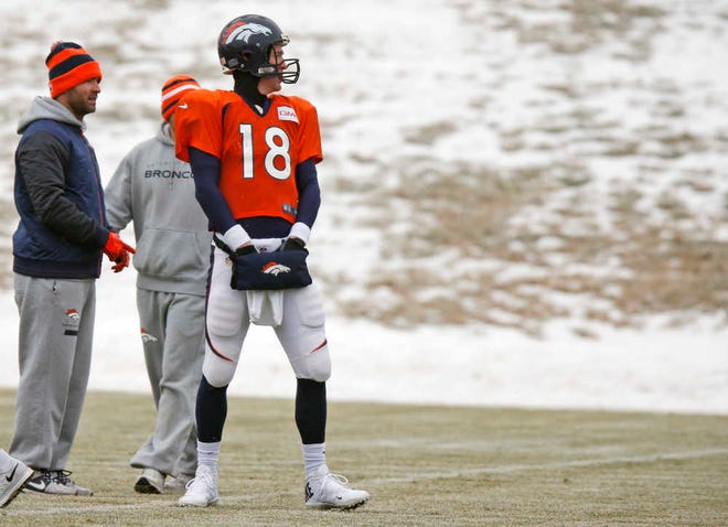 Denver Broncos quarterback Peyton Manning tries to keep his hands warm in a pouch during practice for the team's NFL football divisional playoff game against the Indianapolis Colts Wednesday, Jan. 7, 2015, in Englewood, Colo. (AP Photo/David Zalubowski)