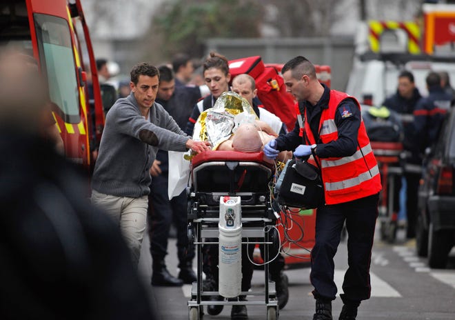 A victim of the Charlie Hebdo shooting is rushed to an ambulance.