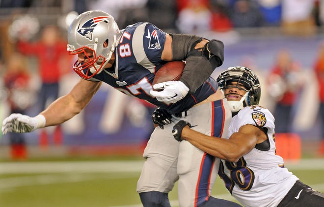 Patriots' Rob Gronkowski is taken down by Baltimore's Rashaan Melvin after gaining a first down, during an AFC Divisional Playoff game, Saturday.