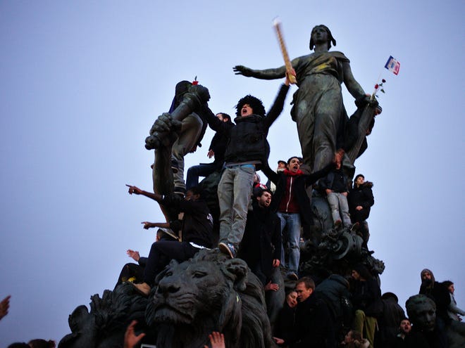 People gather atop a statue at Place de la Nation during a rally in Paris, Sunday, Jan. 11, 2015. Hundreds of thousands gathered Sunday throughout Paris and cities around the world, to show unity and defiance in the face of terrorism that killed 17 people in France's bleakest moment in half a century.