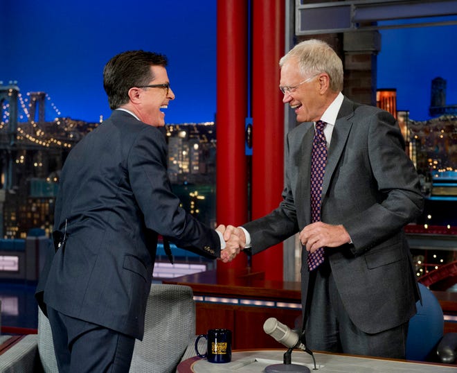 In this April 22, 2014 file photo provided by CBS, Comedy Central's Stephen Colbert, left, shakes hands with host David Letterman on the set of the "Late Show with David Letterman, " in New York. Earlier in April, Letterman announced his retirement in 2015 and CBS announced Colbert as his replacement.