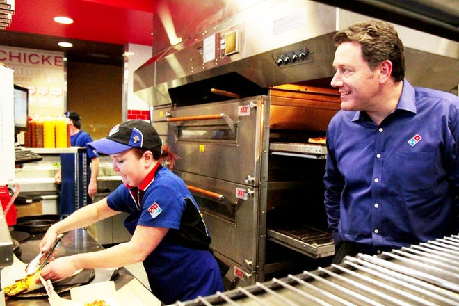 Domino's Pizza CEO Patrick Doyle keeps a close eye on Katie Ritchie as she makes a sandwich at the company's new design store in Seattle. Doyle said the improving U.S. economy has meant more sales for the company.