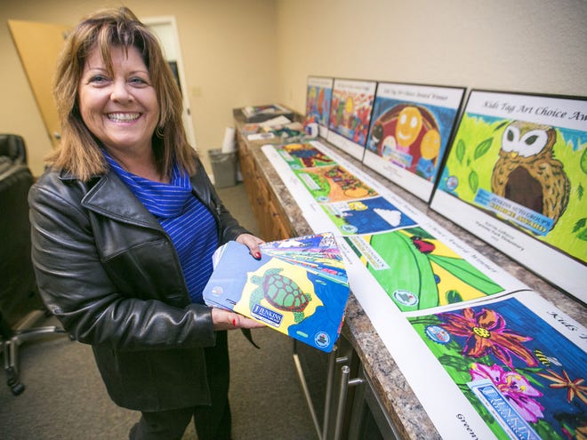 Deborah Dobson looks over some of the winning license plate designs in this year's Kids Tag Art program at the Marion County Tax Collectors office in Ocala on Thursday.