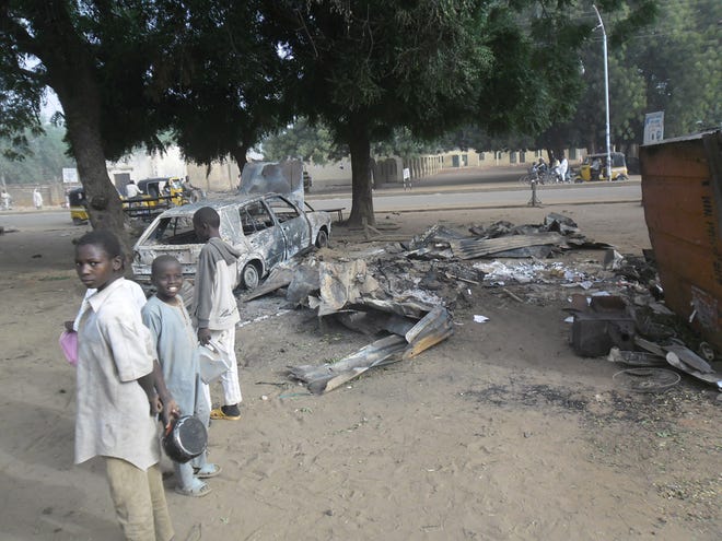 Children stand near the scene of an explosion in a mobile phone market in Potiskum, Nigeria, Monday. Two female suicide bombers targeted the busy marketplace on Sunday.
