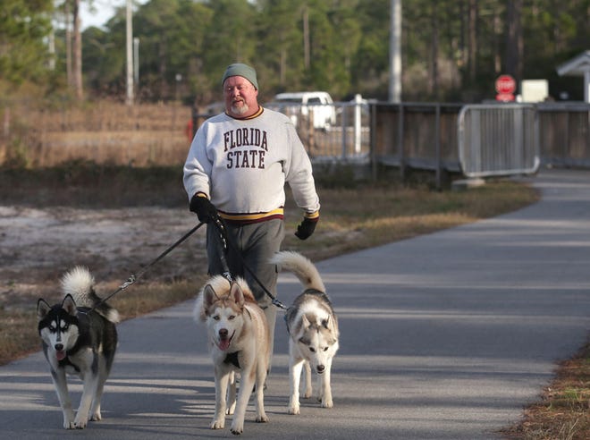 Mike Glaze walks his three huskies, Grimm, from left, Phoenix and Luna, along Gayle's Trails near the proposed expansion site.