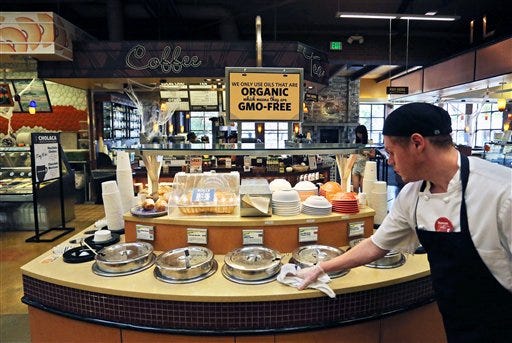 FILE - In this Oct. 23, 2014 file photo, a grocery store employee wipes down a soup bar with a display informing customers of organic, GMO-free oils, in Boulder, Colo. A large majority of Americans support labeling of genetically modified foods, whether they care about eating them or not. According to a December Associated Press-GfK poll, 66 percent of Americans favor requiring food manufacturers to put labels on products that contain genetically modified organisms, or foods grown from seeds engineered in labs. Only seven percent are opposed to the idea, and 24 percent are neutral. (AP Photo/Brennan Linsley, File)