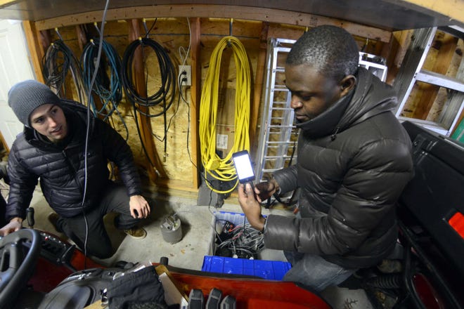Boston College graduate students Stephen Hilfiker, left, and Oluwaseun Fadugba place a seismometer in the garage of Bob Colli's home in Plainfield on Tuesday to detect earthquakes.