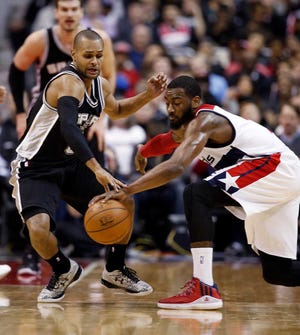 San Antonio Spurs guard Patty Mills (8), from Australia, reaches for the ball against Washington Wizards guard John Wall (2) during the second half of an NBA basketball game, Tuesday, Jan. 13, 2015, in Washington. The Wizards won 101-93. (AP Photo/Alex Brandon)