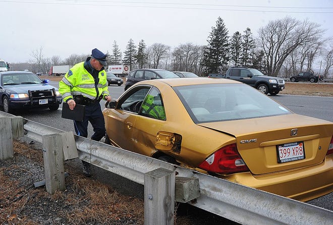 Massachusetts State Police Trooper Michael Halstead investigates one of several motor vehicle crashes that occurred Thursday morning on Interstate 195 after freezing rain swept across the area.