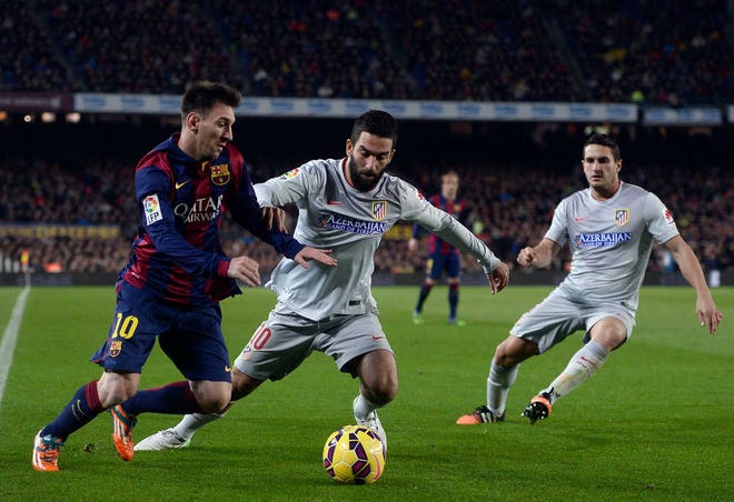 FC Barcelona's Lionel Messi, from Argentina, left, duels for the ball against Atletico Madrid's Arda Turan during a Spanish La Liga soccer match at the Camp Nou stadium in Barcelona, Spain, Sunday, Jan. 11, 2015. (AP Photo/Manu Fernandez)