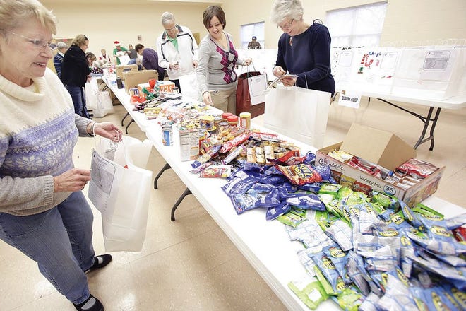 Faith in Action volunteers fill hand decorated bags donated with artwork by the 2nd and 5th graders from Amherst Elementary School. The food and necessary personal items were all donated and will benefit those that live alone in the Massillon area.