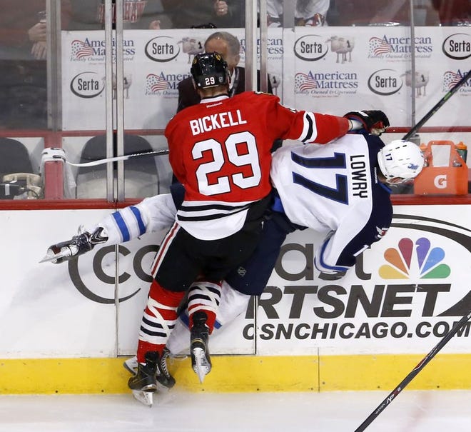 Chicago Blackhawks left wing Bryan Bickell (29) flips Winnipeg Jets left wing Adam Lowry against the boards during the first period of an NHL hockey game Friday in Chicago.