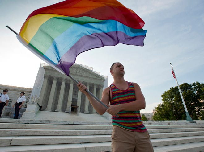 FILE - In this June 26, 2013, file photo, gay rights advocate Vin Testa waves a rainbow flag in front of the Supreme Court in Washington. The justices might have to decide to jump in at their closed-door conference on Friday, Jan. 16, 2015, if they want to resolve the legal debate over gay marriage in the next few months. The justices would hear the case in April, the last month for oral arguments before the next term begins in October. (AP Photo/J. Scott Applewhite, File)