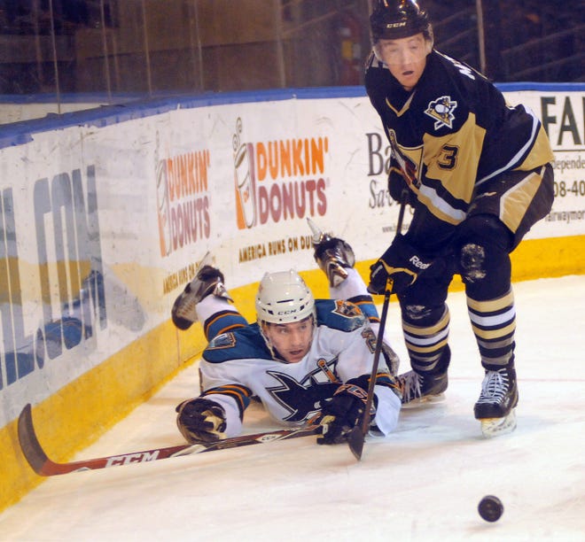 The Sharks' Dylan DeMelo falls to the ice, as he battles the Penguins' Reid McNeill for a loose puck behind the net.
