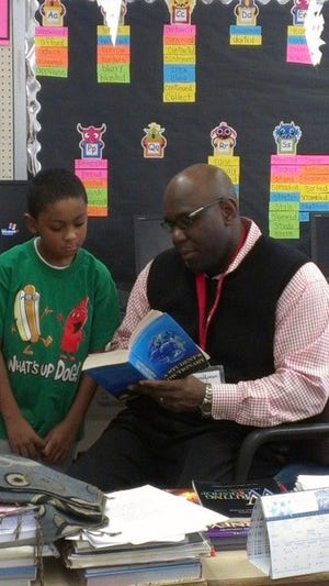 State Assemblyman Troy Singleton, D-7th of Palmyra, helps third grader Ky'Ree Smith find a word in the dictionary during his stint at teacher for the day Thursday at Hawthorne Elementary School.